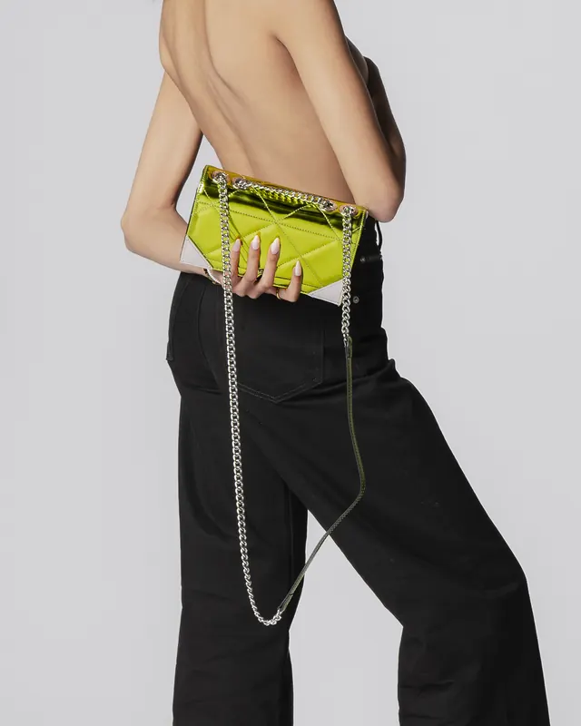 Back view of a topless model in black jeans holding a chartreuse quilted clutch with a silver chain